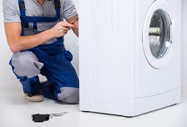 A mechanic disassembles a washing machine