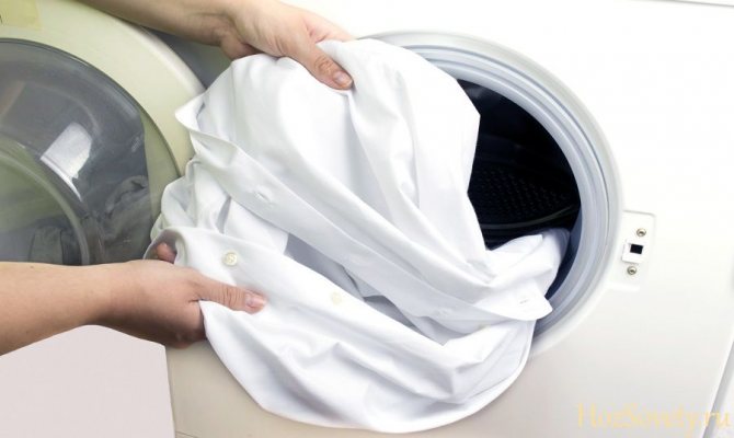loading a shirt into the washing machine